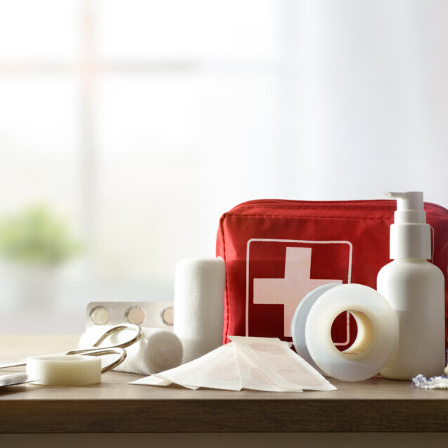 Basic home kit for cures in domestic accidents on a wooden table in a room. Horizontal composition. Front view.