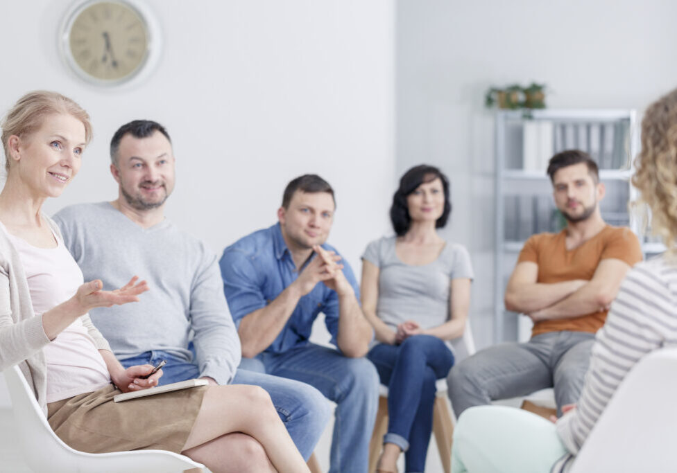 Therapist congratulating young woman on her progress in therapy and happy family blurry in the background